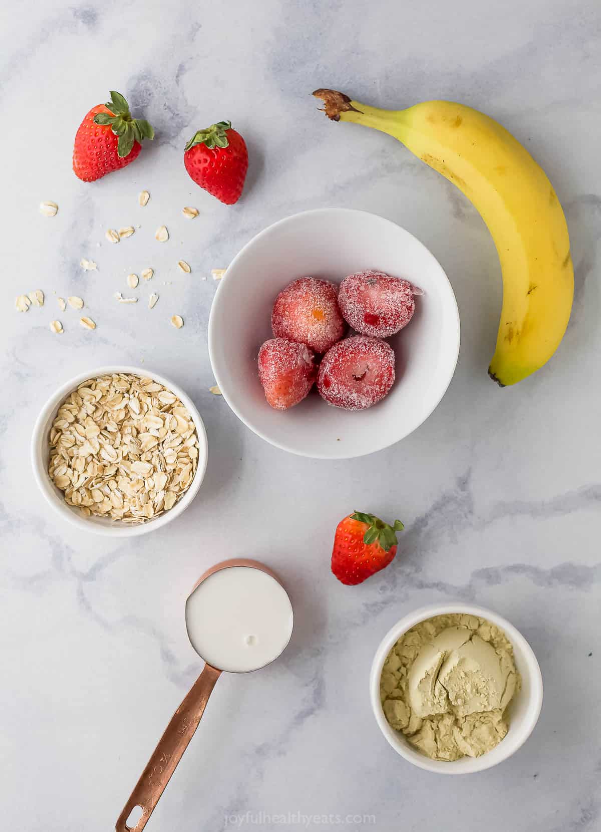 A banana, almond milk, oats and the remaining smoothie ingredients on a countertop