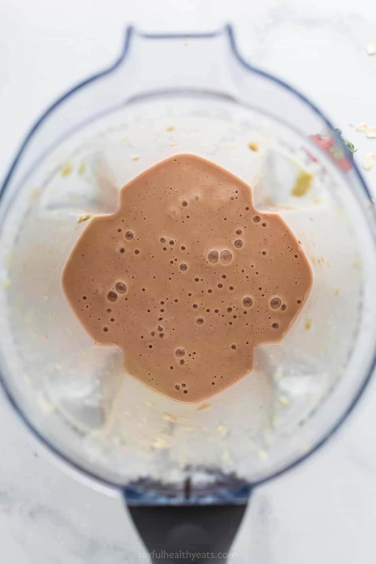 The blended smoothie ingredients inside of a large blender on top of a marble counter