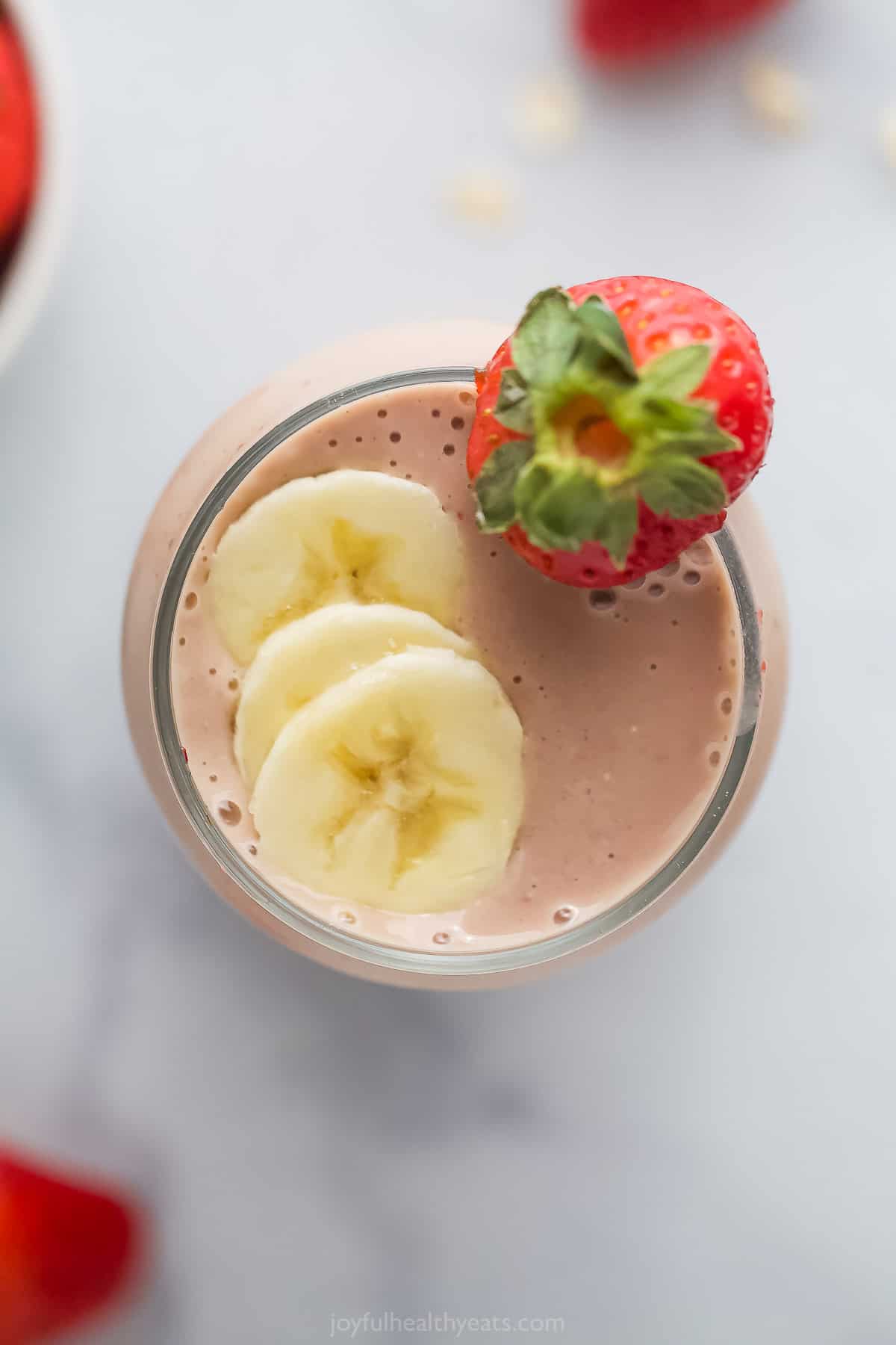 A strawberry banana smoothie in a large glass shown from the top