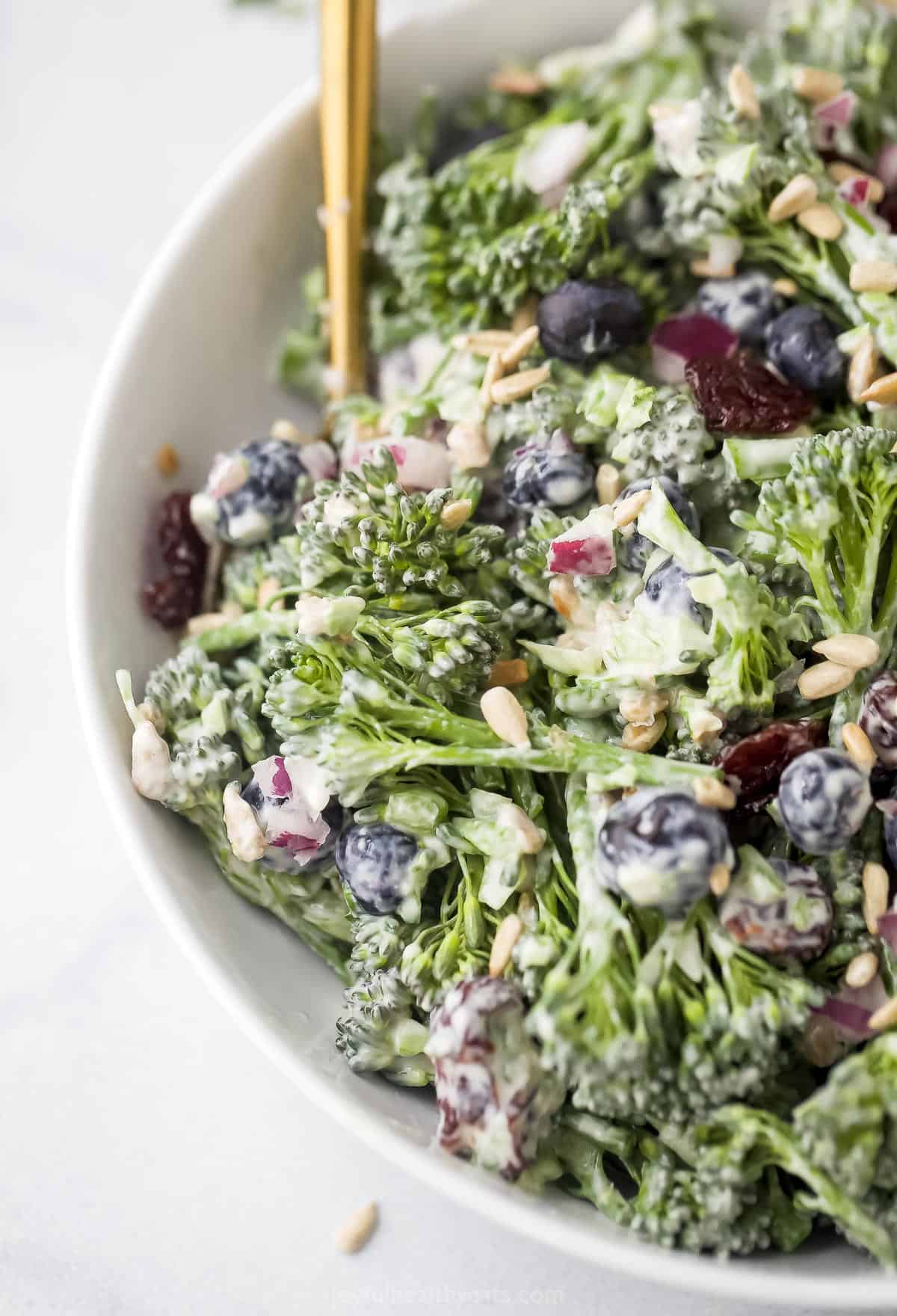 A close-up shot of a bowl of healthy broccolini salad sitting on top of a kitchen counter
