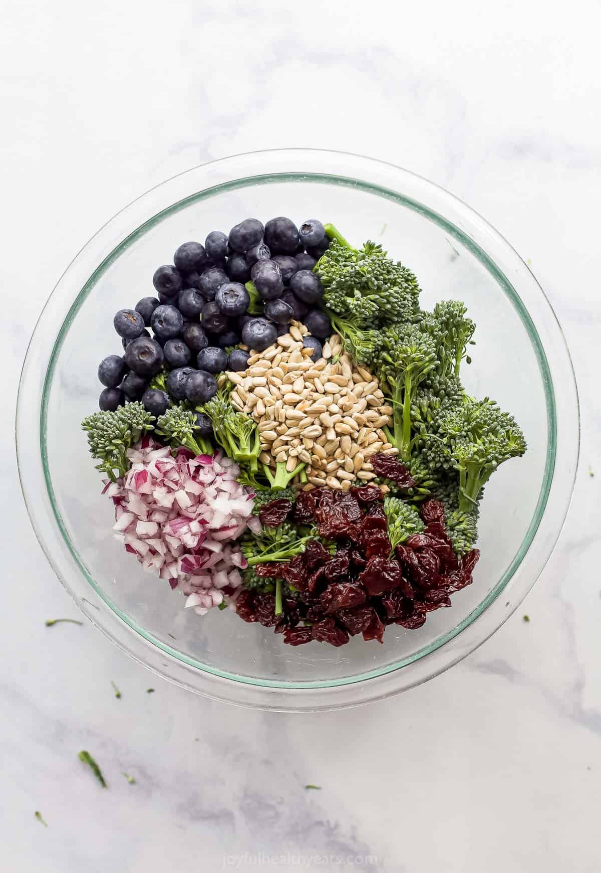 All of the broccolini salad ingredients in a large mixing bowl on top of a marble surface