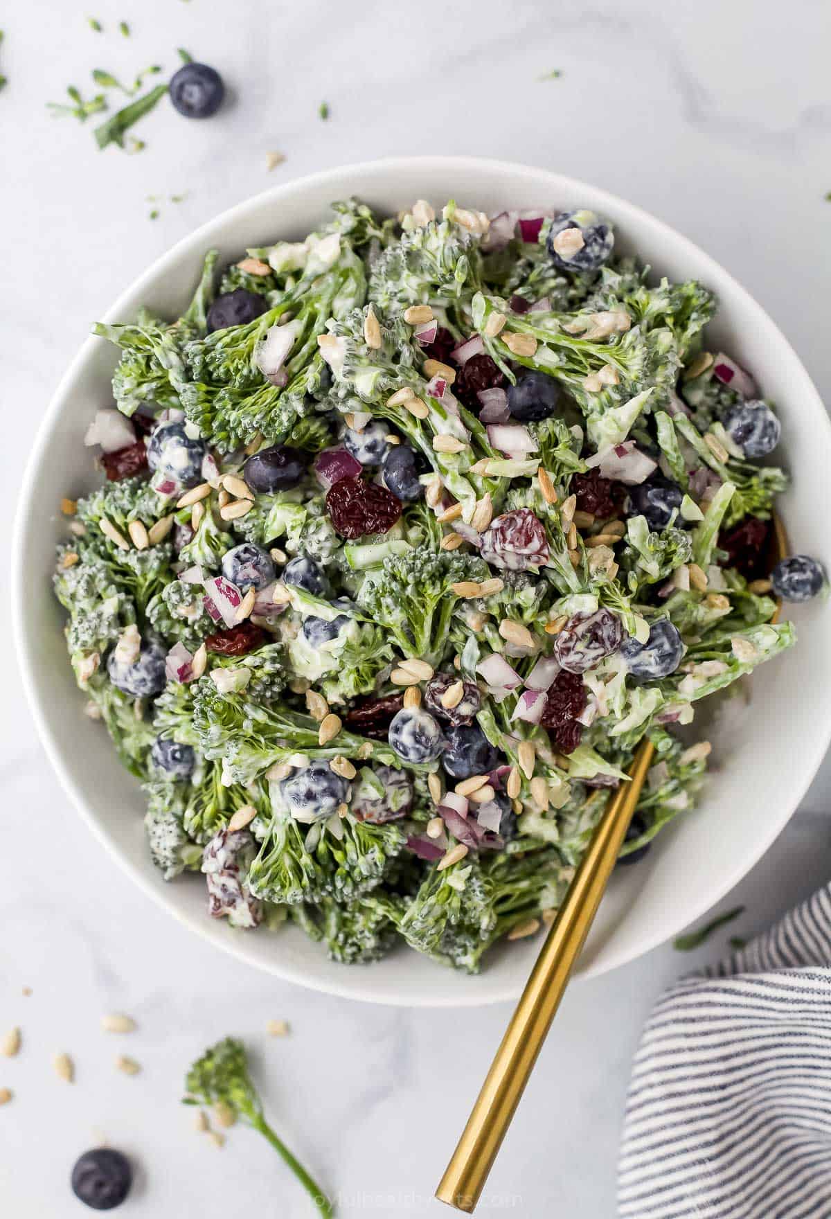 A broccolini salad with yogurt dressing in a bowl on a marble countertop