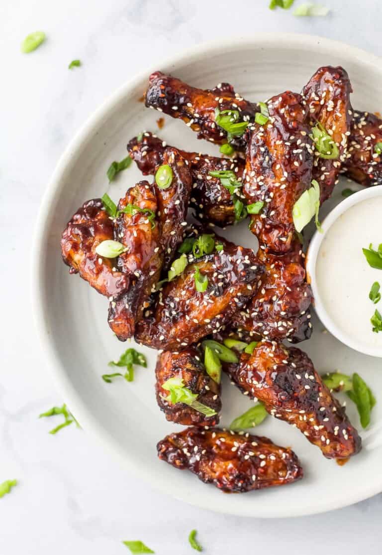 baked chicken wings asian style on a plate garnished with sesame and green onion