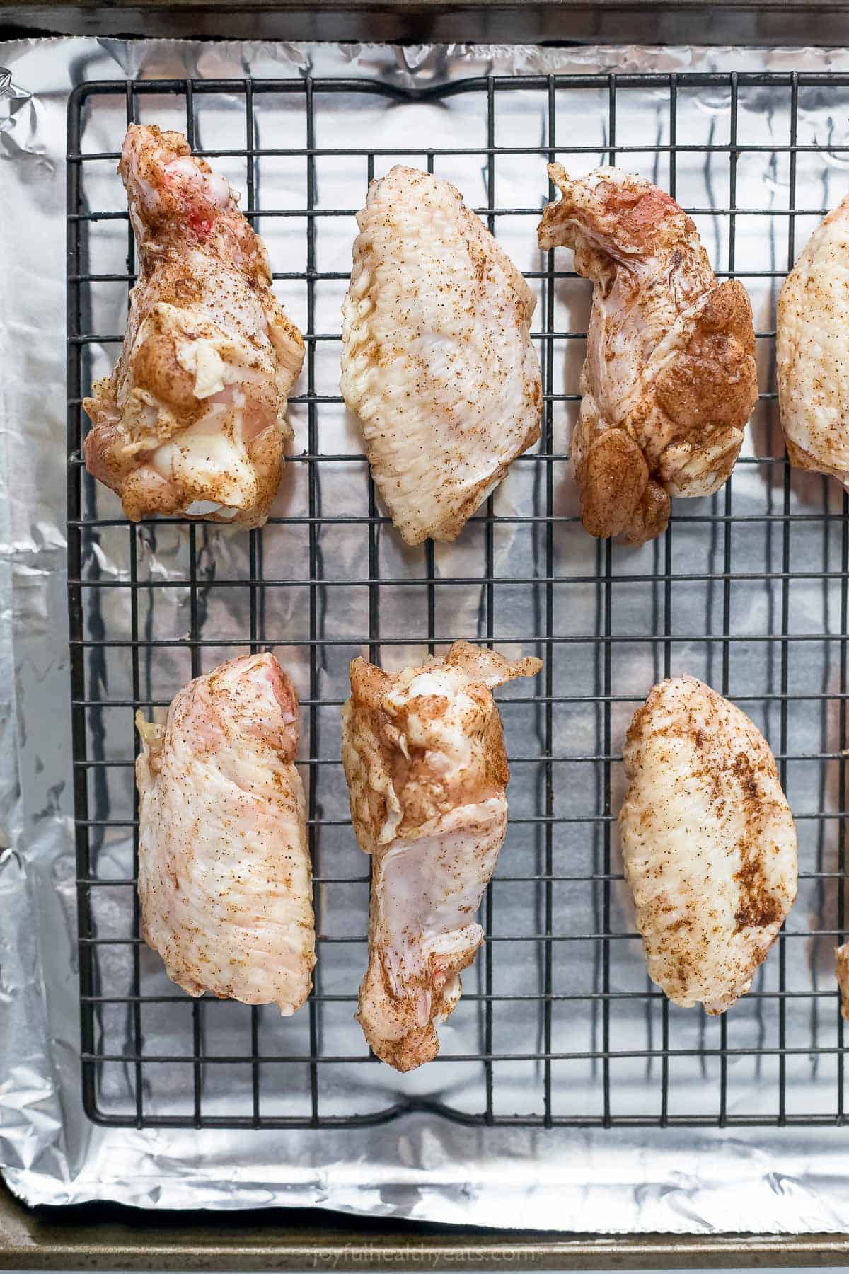 seasoned raw chicken wings on a baking sheet