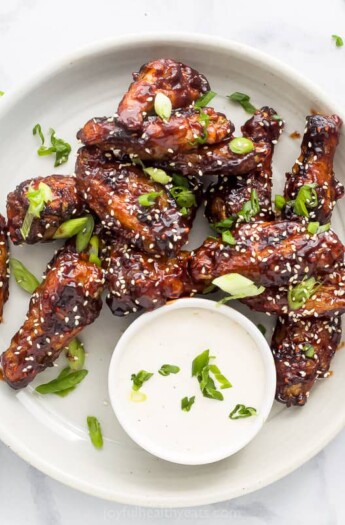 asian chicken wings on a plate garnished with sesame seeds and green onion