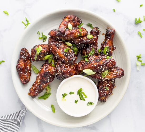 asian chicken wings on a plate garnished with sesame seeds and green onion