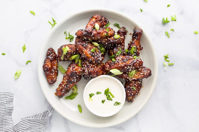 asian chicken wings on a plate garnished with sesame seeds and green onion