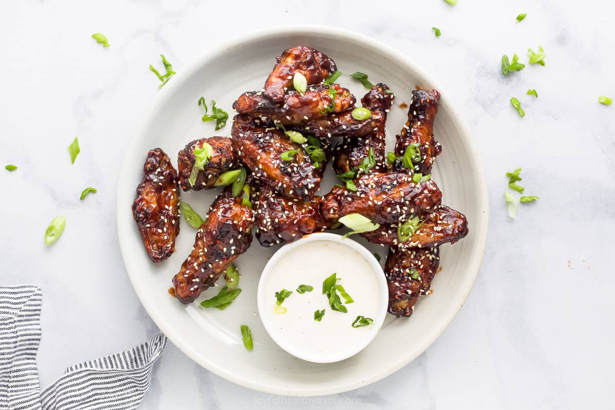 asian chicken wings on a plate garnished with sesame seeds and green onion