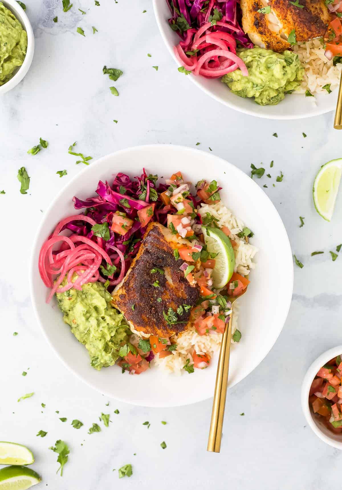 A Baja bowl on a countertop beside a dish of guac and a second Baja bowl