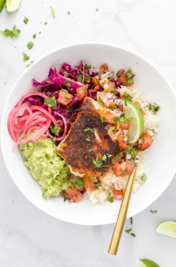 A Baja fish taco bowl on a granite countertop with a spoon inside the bowl