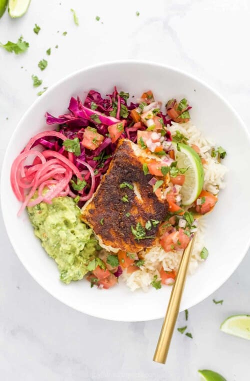 A Baja fish taco bowl on a granite countertop with a spoon inside the bowl