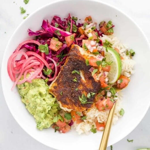 A Baja fish taco bowl on a granite countertop with a spoon inside the bowl