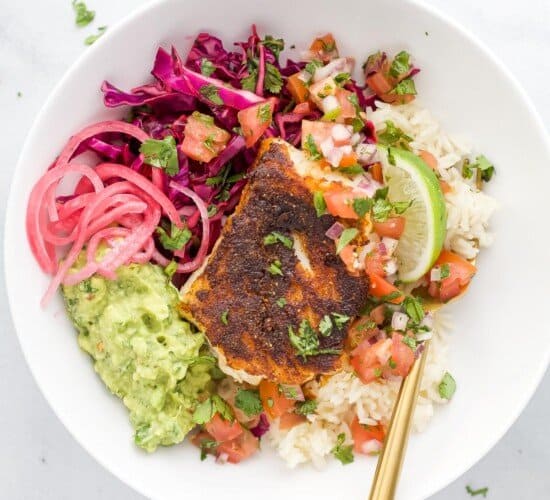 A Baja fish taco bowl on a granite countertop with a spoon inside the bowl