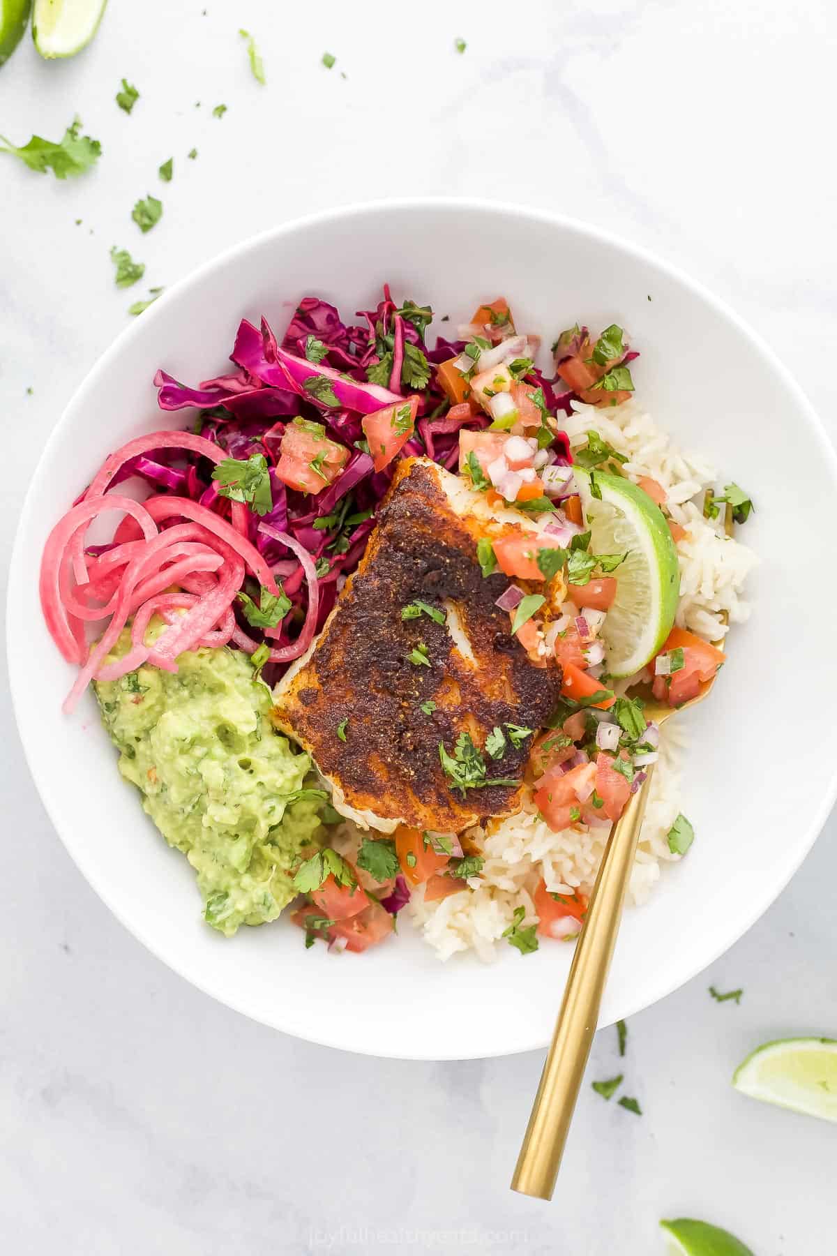 A Baja fish taco bowl on a granite countertop with a spoon inside the bowl