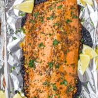 A foil-lined baking sheet with a baked Dijon maple glazed salmon fillet on top of it