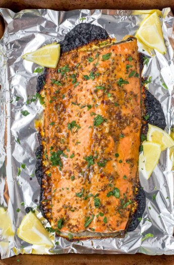 A foil-lined baking sheet with a baked Dijon maple glazed salmon fillet on top of it