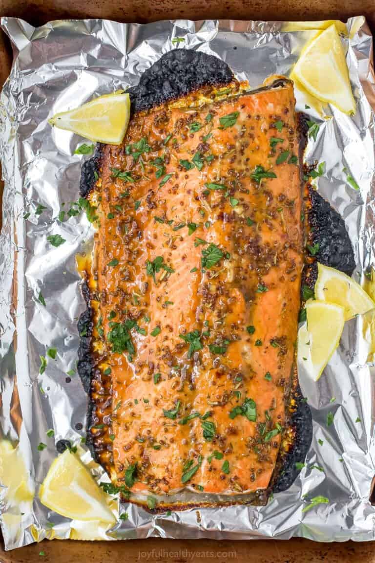 A foil-lined baking sheet with a baked Dijon maple glazed salmon fillet on top of it