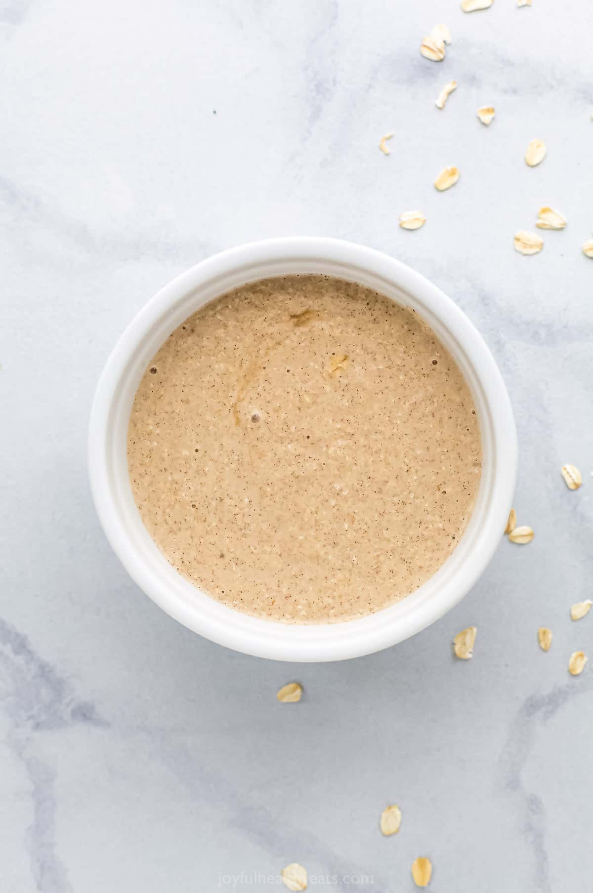 The blended oat mixture inside of a 4-inch ramekin on top of a marble counter