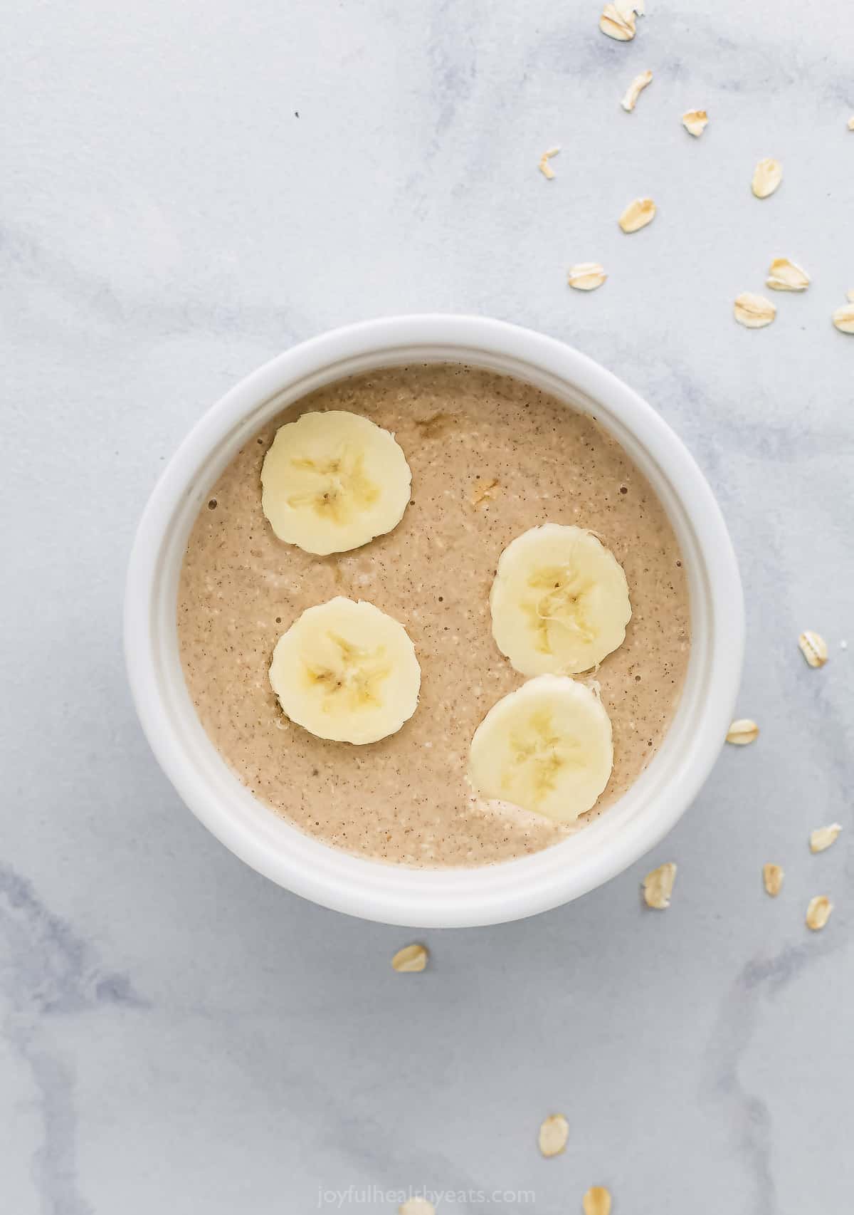 An eight-ounce ramekin filled with the blended oat mixture with four banana slices on top