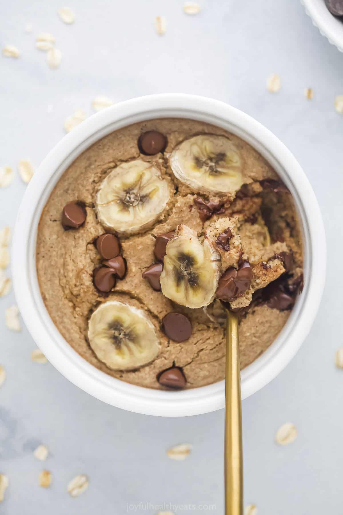 A spoon scooping out a bite of chocolate peanut butter baked oatmeal from a ramekin