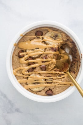 Warm baked oatmeal inside of a ramekin with a drizzle of melty peanut butter on top