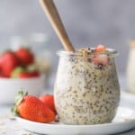 Vanilla almond overnight oats in a jar on a plate with a bunch of fresh berries in the background