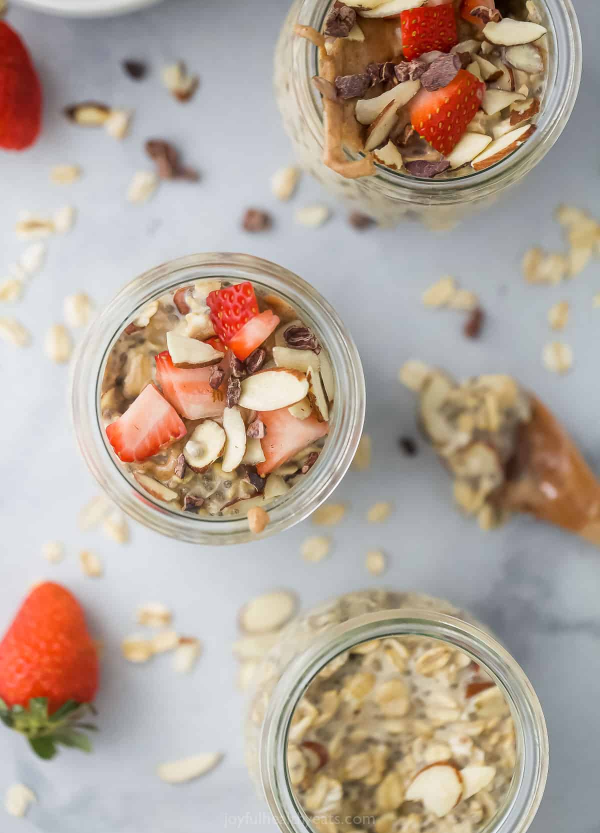 Three servings of vanilla almond oatmeal in separate jars on a granite countertop