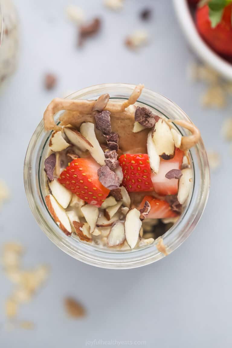 a mason jar with almonds, strawberries, chocolate shavings, and peanut butter drizzle 