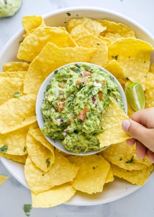 guacamole in a bowl with chips around it