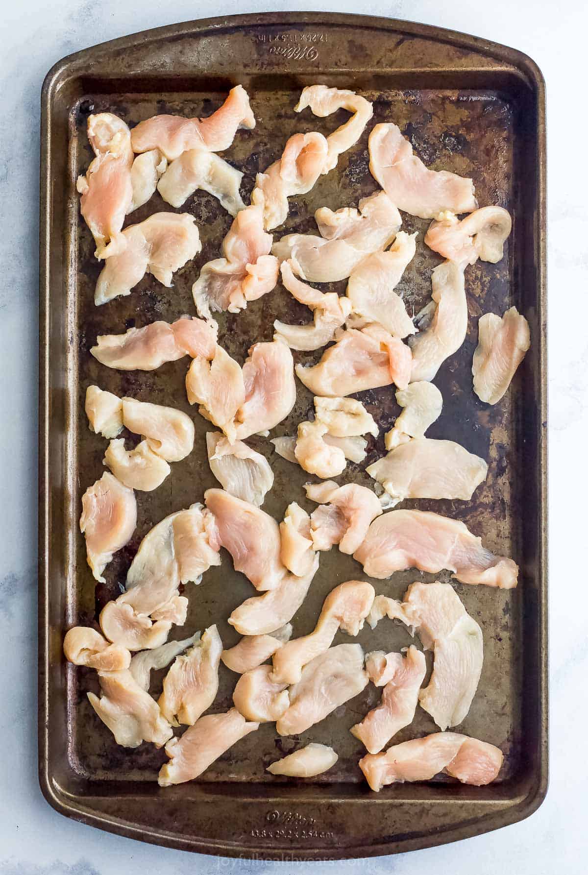 Slices of chicken breast on a baking sheet