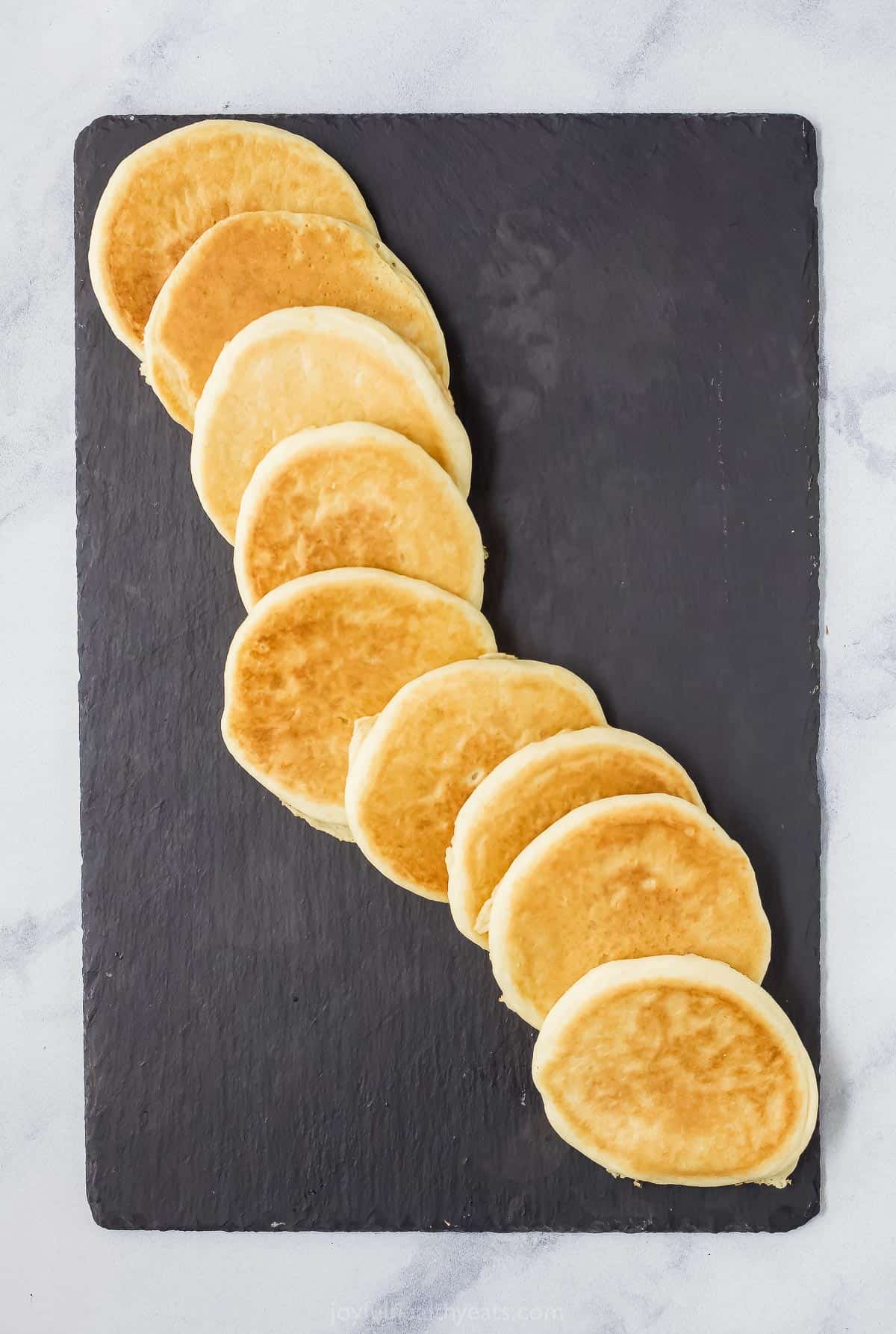 Pancakes lined up diagonally from corner to corner of a cheese board