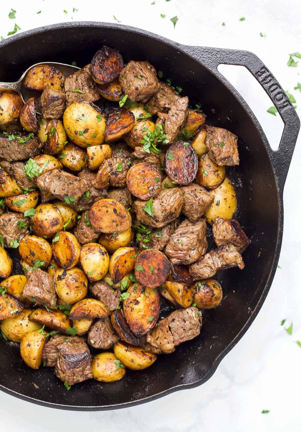 Overhead view of garlic butter steak bites and potatoes in a skillet