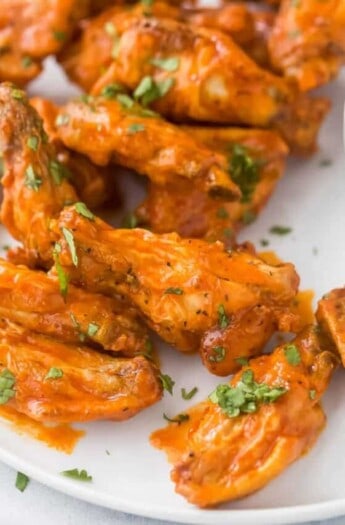 A close-up shot of chicken wings on a plate garnished with finely chopped parsley