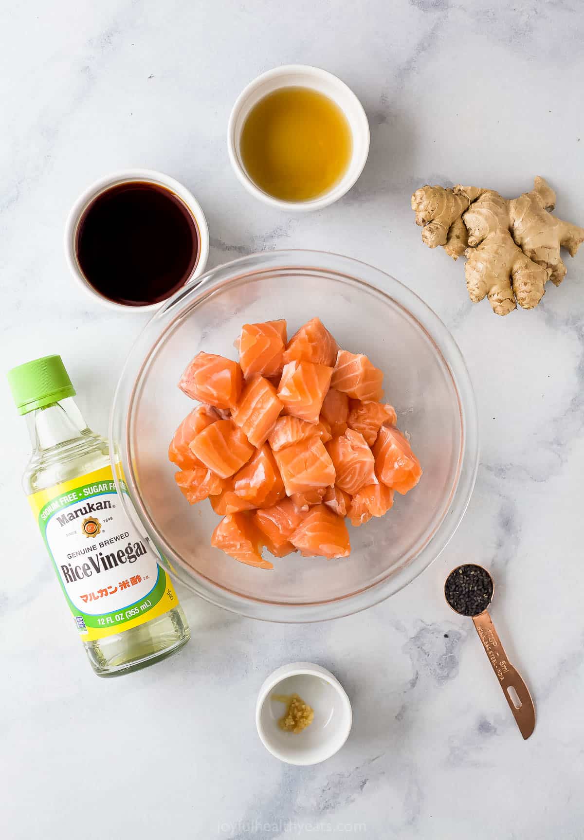 Cubes of salmon, rice wine vinegar, tamari and the rest of the marinade ingredients on a kitchen countertop