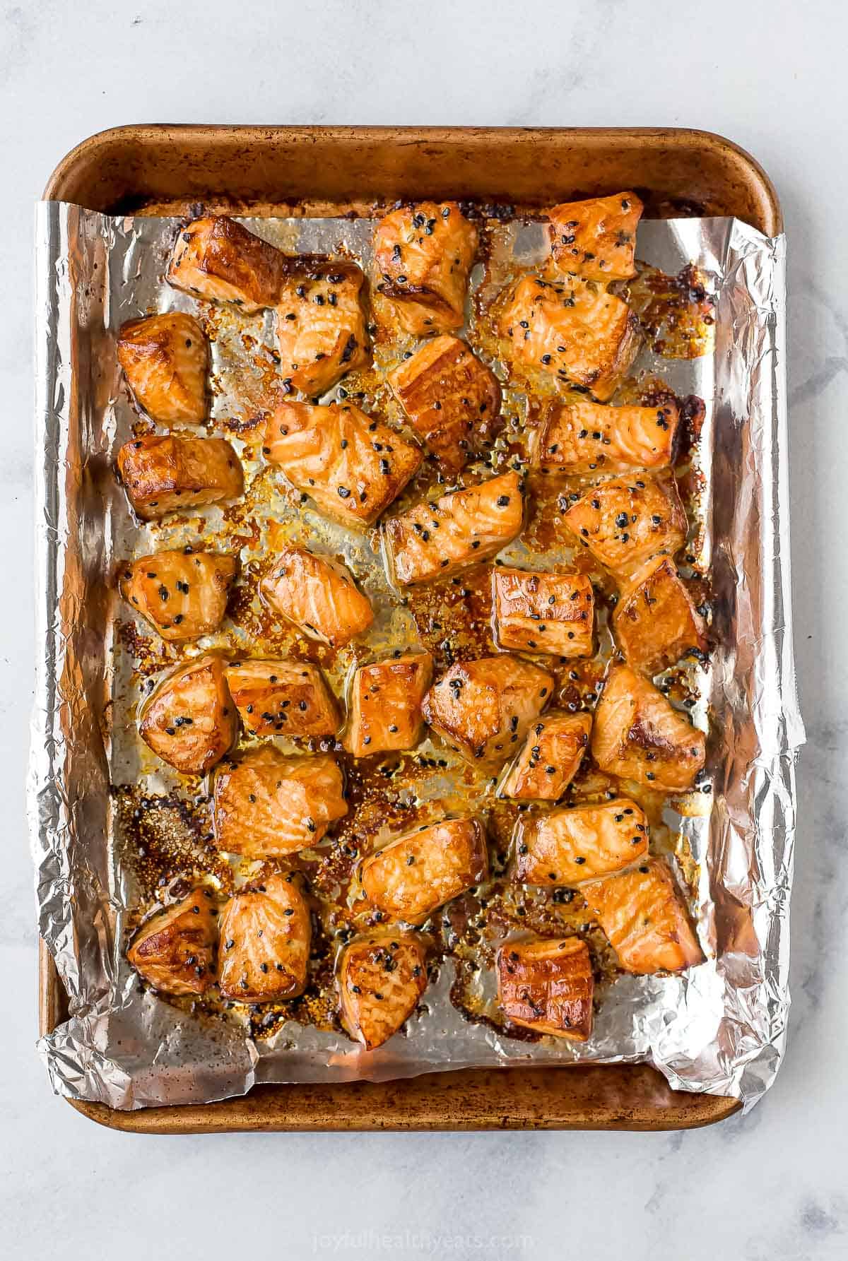 Marinated and baked cubes of salmon on a foil-lined baking sheet