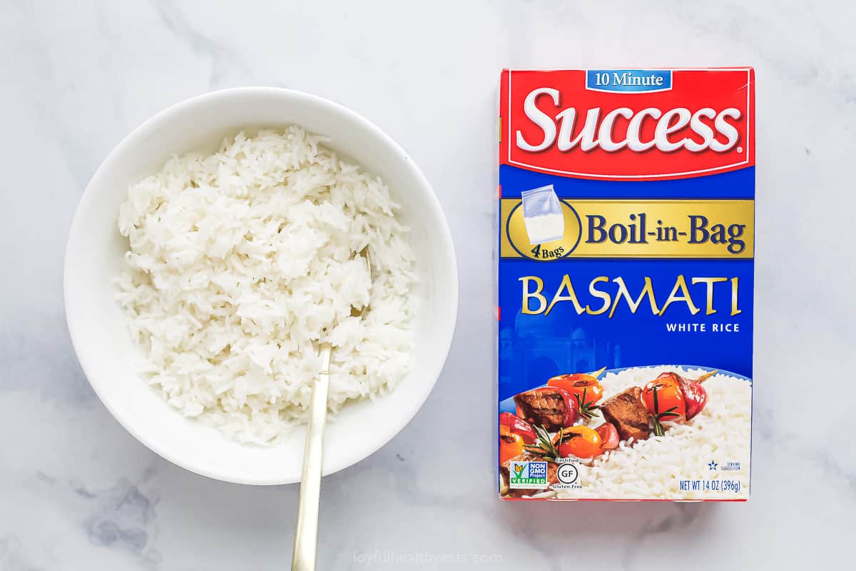 A boil of cooked basmati rice beside the packaging for the rice
