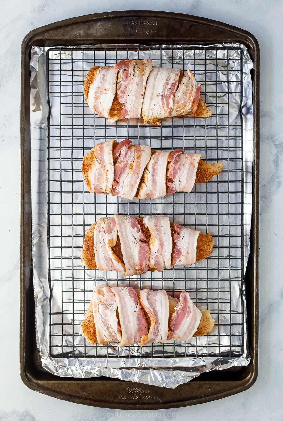 Chicken breasts wrapped in bacon on a baking sheet