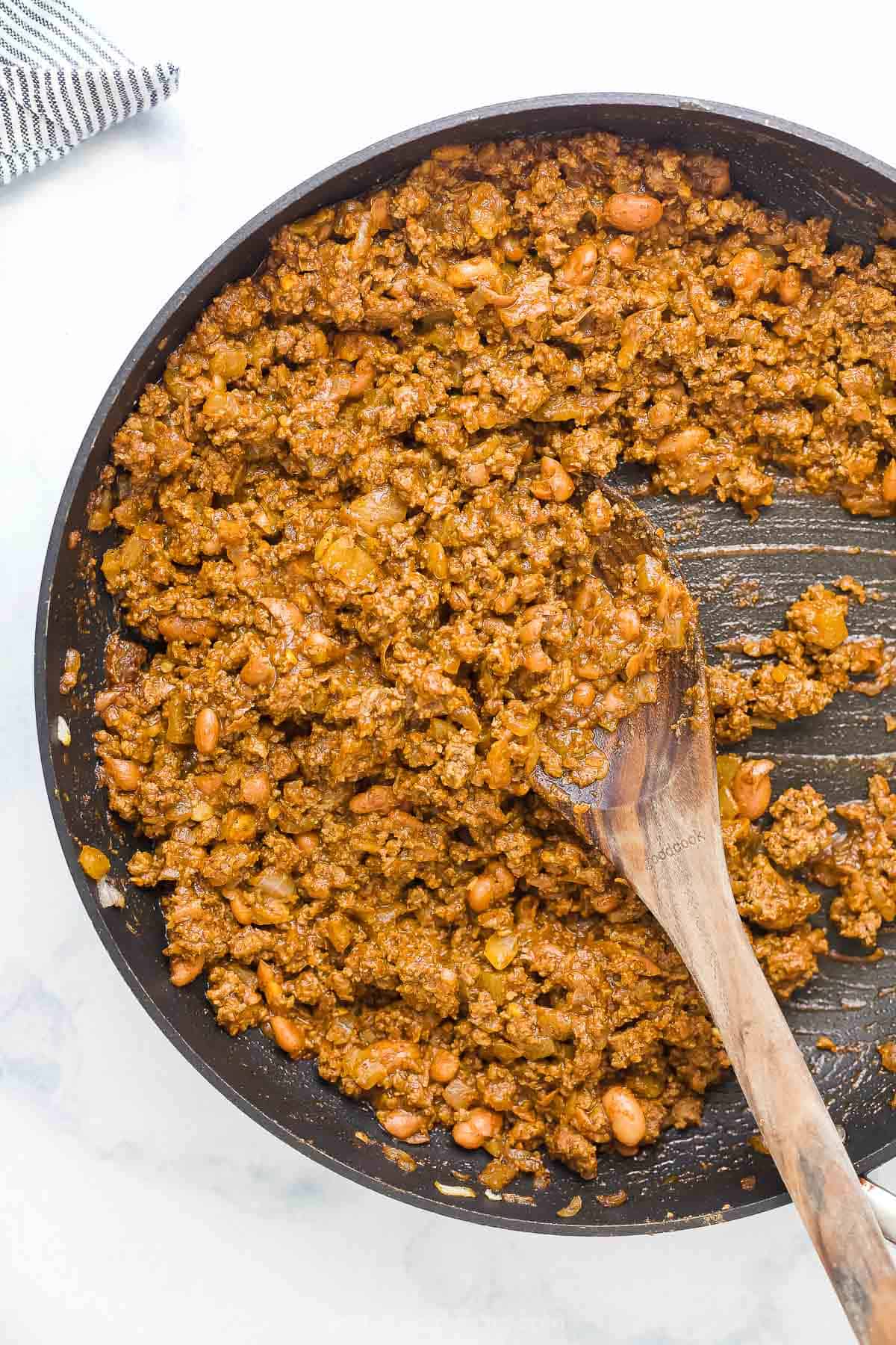 ground beef mixture in a pan with wooden spoon