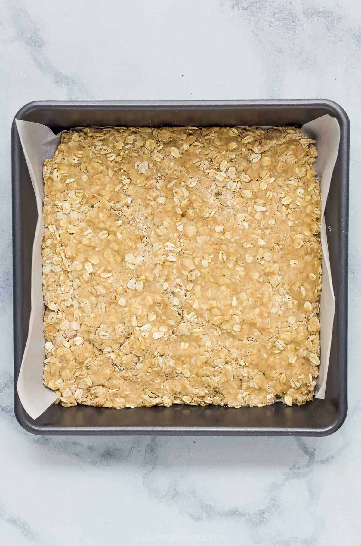The oatmeal mixture pressed into a square pan lined with parchment paper
