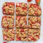 Nine strawberry oatmeal bars on top of a sheet of parchment paper
