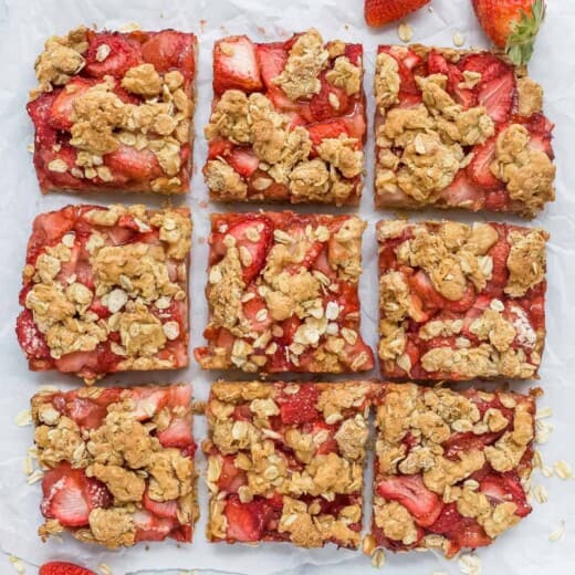 Nine strawberry oatmeal bars on top of a sheet of parchment paper