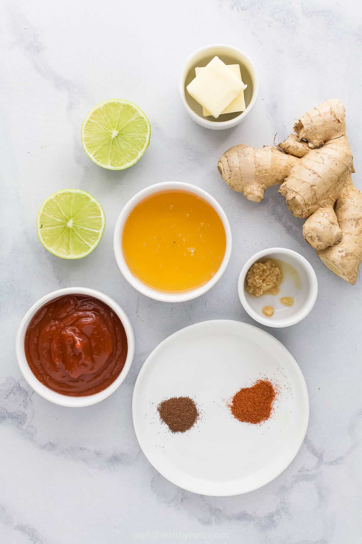 Fresh ginger, honey, fresh lime halves and the rest of the ingredients on a marble countertop