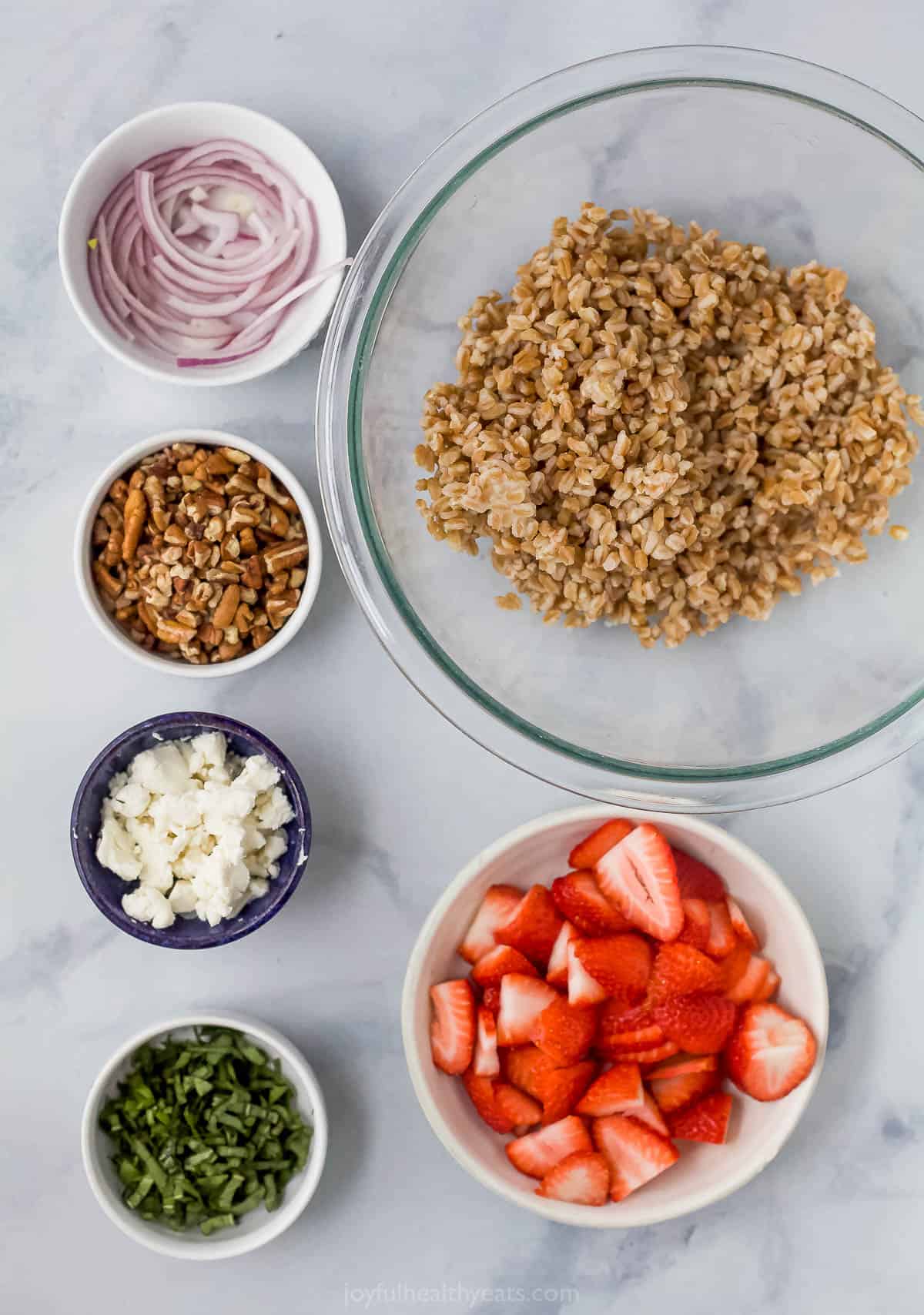 A bowl of chopped pecans, a bowl of crumbled goat cheese and the rest of the ingredients in separate bowls on a countertop