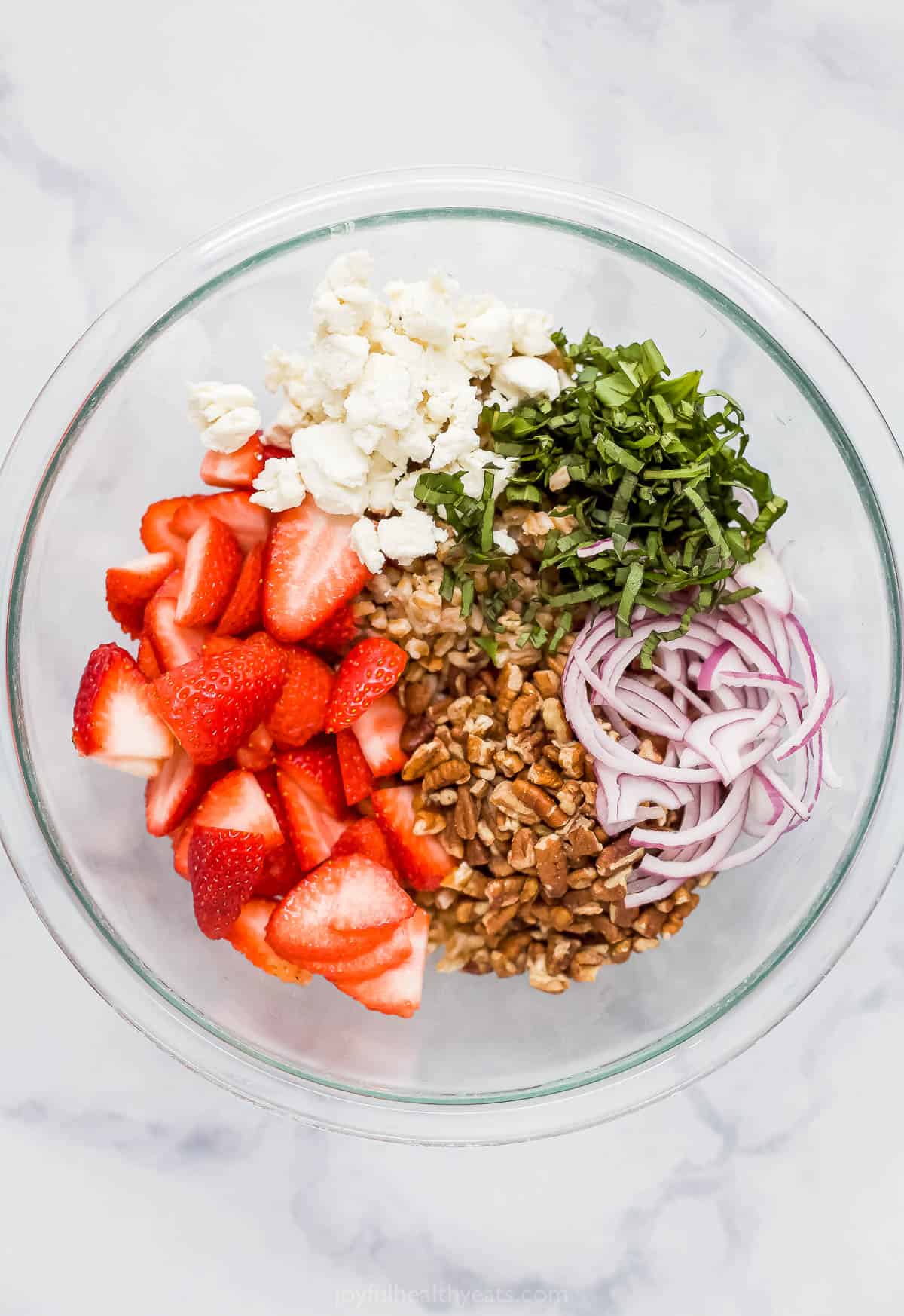 All of the salad ingredients inside of a large glass mixing bowl