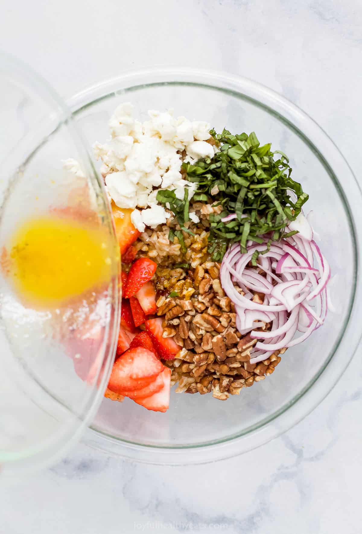 Citrus dressing being poured over the bowl filled with salad ingredients