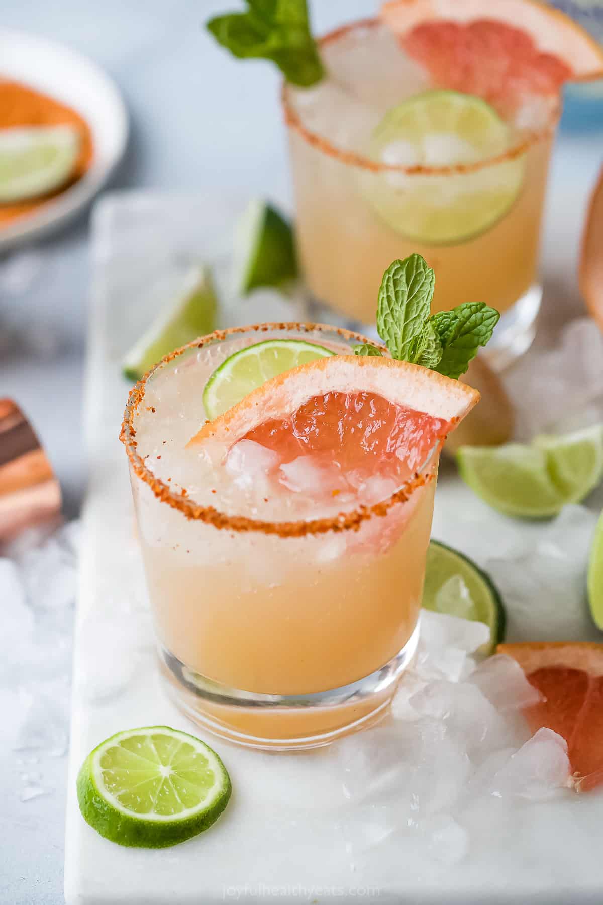 Two Paloma cocktails on top of a cutting board on a kitchen countertop