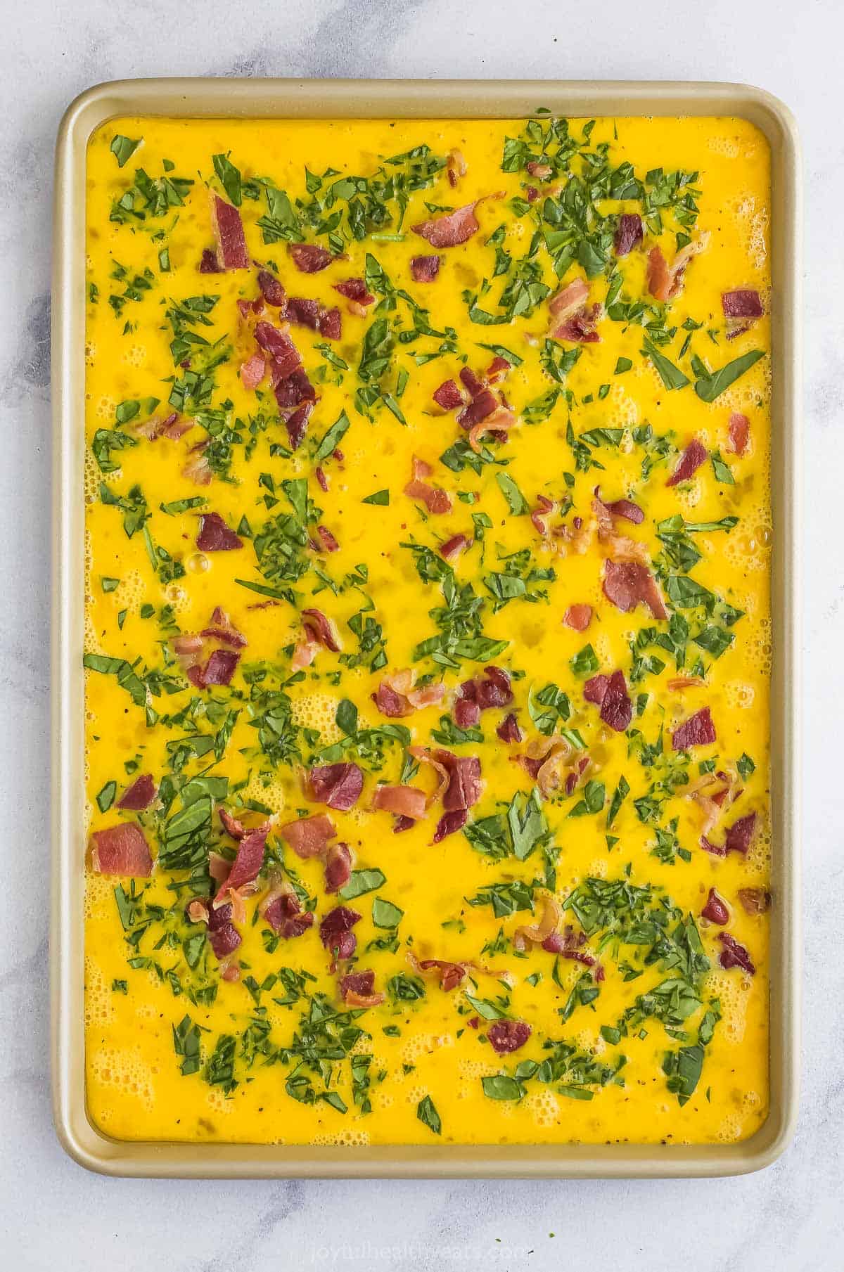 The baking sheet full of frittata batter after the bacon has been added