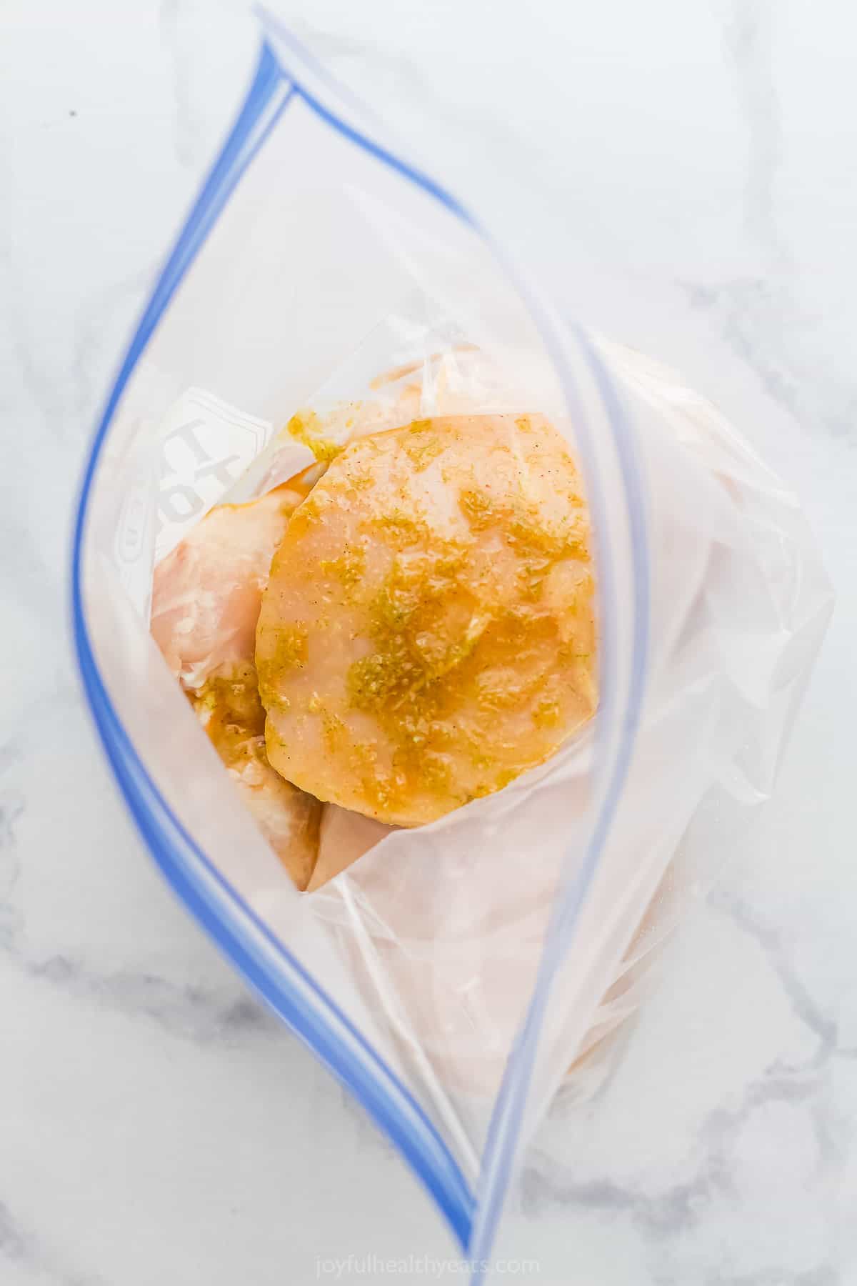 Raw chicken breasts inside of a Ziploc bag with the marinade