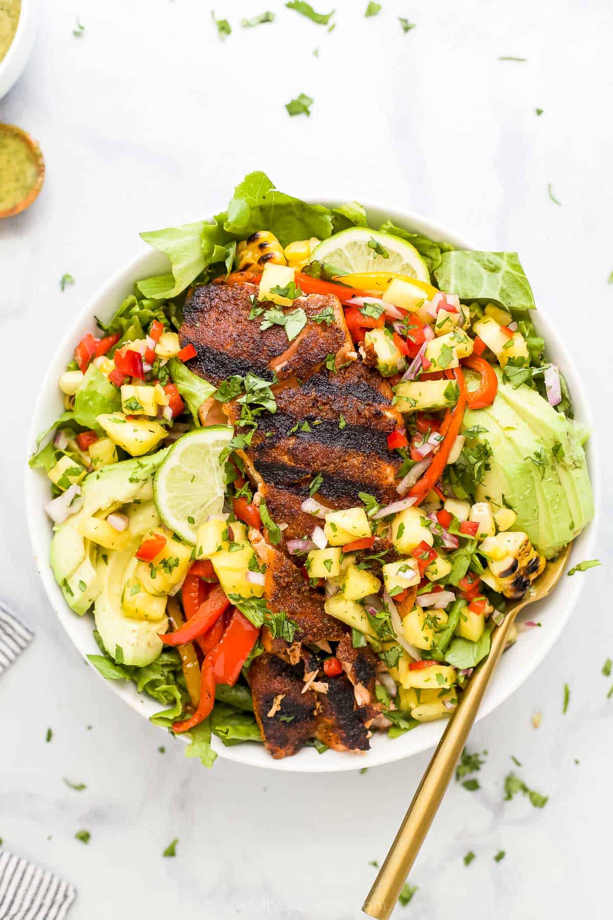 Salmon salad in a bowl on a countertop with chopped herbs sprinkled on top