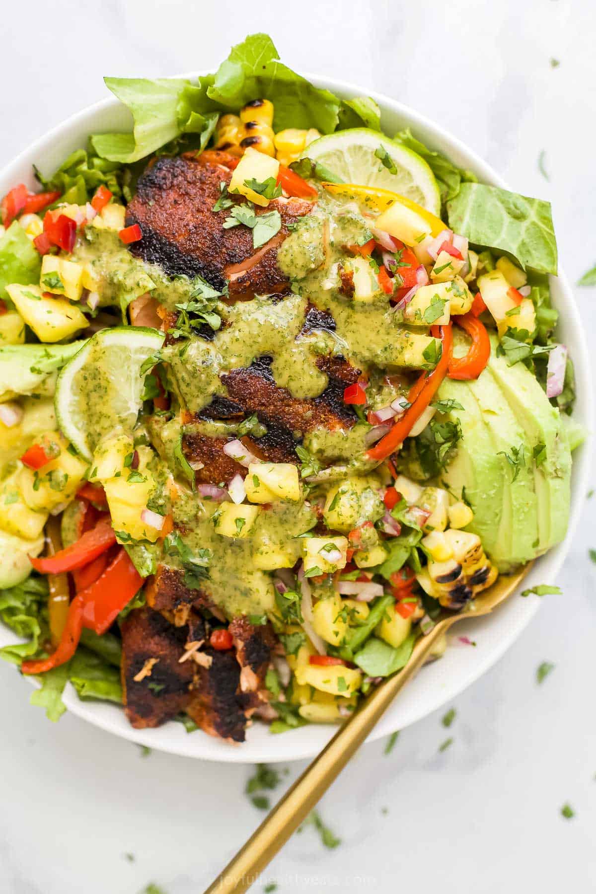 A salmon salad in a large bowl with a golden spoon inside.